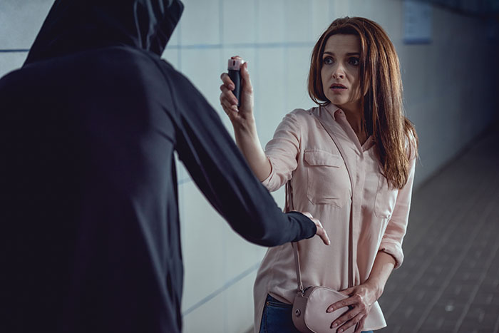 Woman using pepper spray to defend herself from an attacker, demonstrating unhinged safety habits that might save lives.