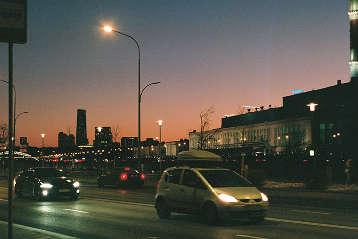 City street at dusk with cars driving under streetlights, illustrating unhinged safety habits that might save lives.