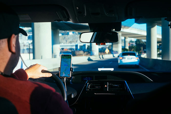 Man driving a car under overpasses with GPS navigation visible, illustrating safety habits that might save lives.
