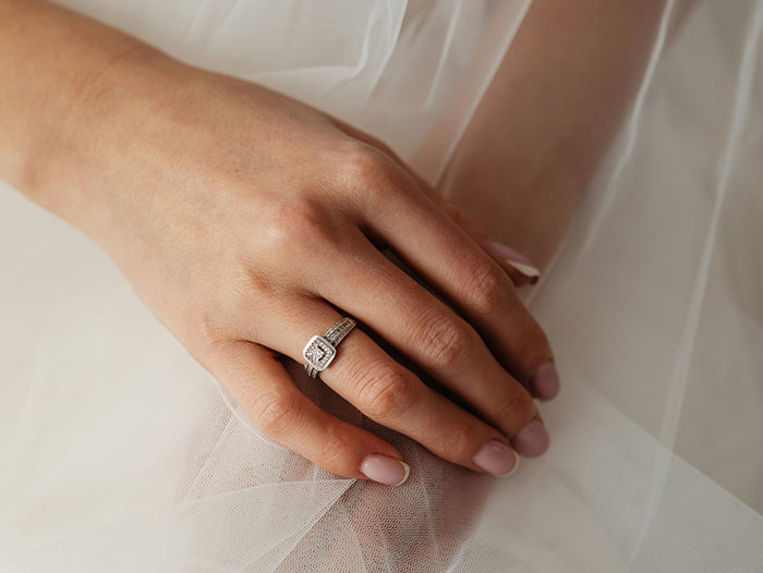 Close-up of a hand with a diamond ring resting on soft white fabric, evoking eerie sea stories and mysterious experiences.