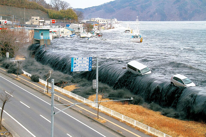 Tsunami wave flooding coastal area with vehicles swept away, illustrating one of the creepiest things witnessed by people who worked at sea.