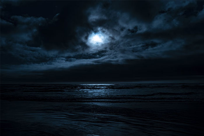 Dark ocean scene at night with moonlight reflecting on waves, evoking eerie experiences shared by people who worked at sea.