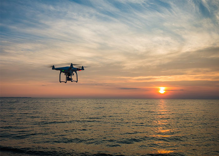 Drone flying over calm sea during sunset capturing eerie seascape, reflecting creepy moments witnessed by people who worked at sea.