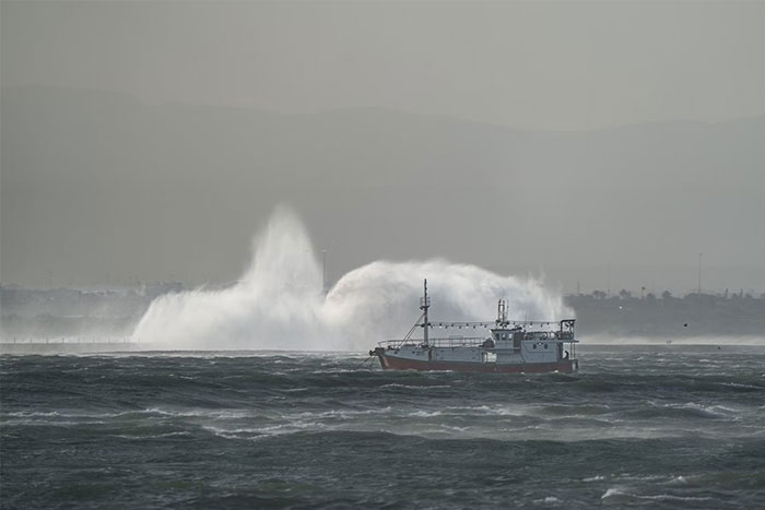 Fishing boat on rough sea with large waves crashing in the background, capturing eerie moments witnessed at sea.