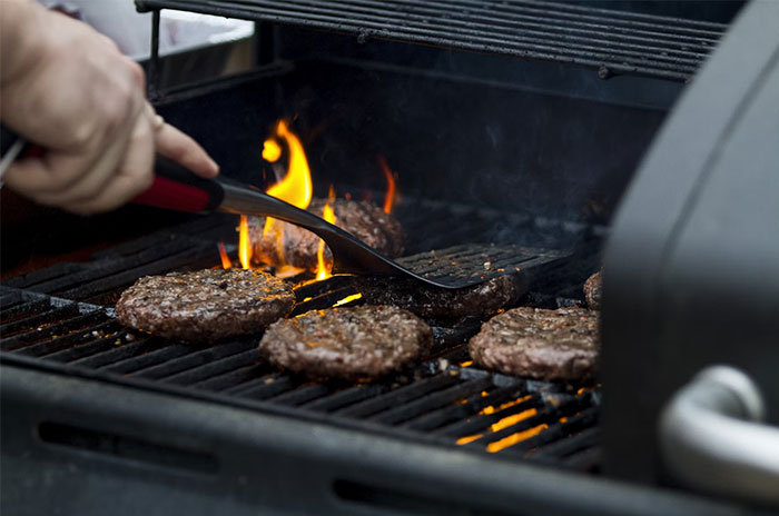 Regular people grilling burgers on an outdoor barbecue, getting a glimpse into the world of the ultra wealthy.