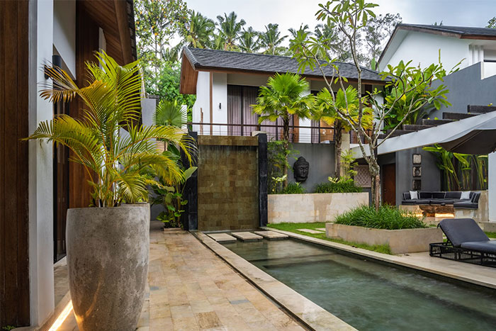 Luxurious modern outdoor pool and garden area showcasing the lifestyle of the ultra wealthy in a tropical setting.