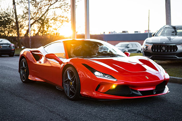 Red luxury sports car with driver, showcasing a glimpse into the world of the ultra wealthy at sunset.