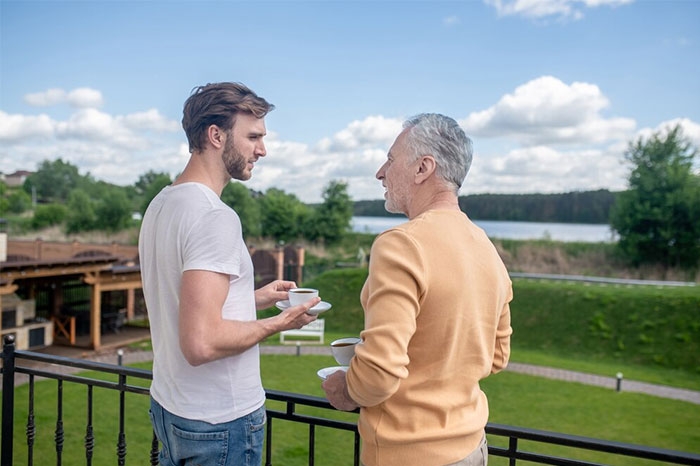 Two men enjoying coffee on a balcony overlooking a luxurious estate, offering a glimpse into the world of the ultra wealthy.