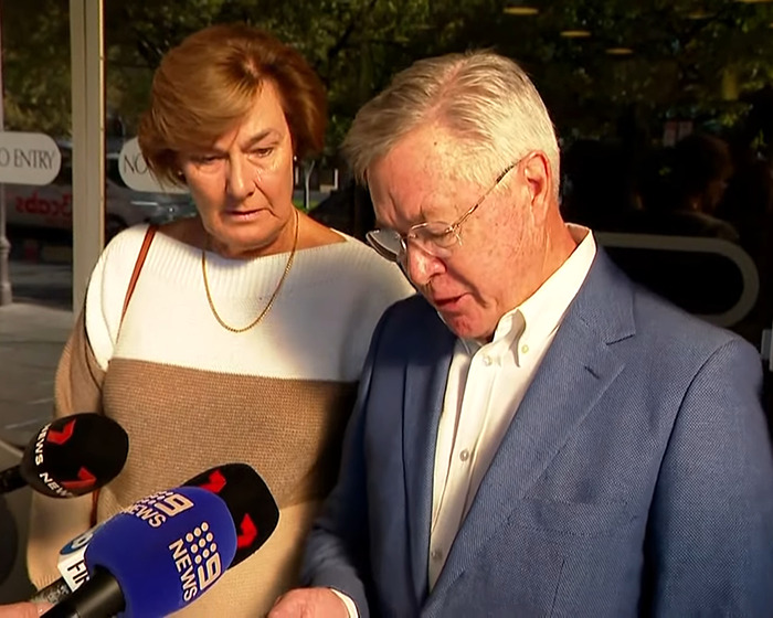 An older man and woman speaking to reporters outside, addressing a fatal crash involving a cyclist and Olympian wife.