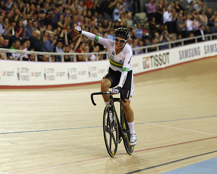 Cyclist celebrating on indoor track cycling velodrome with crowd in background, related to apology and fatal crash news.