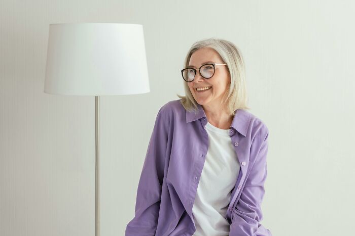 Smiling elderly woman with glasses sitting by a lamp, symbolizing the worlds oldest human and longevity secret.