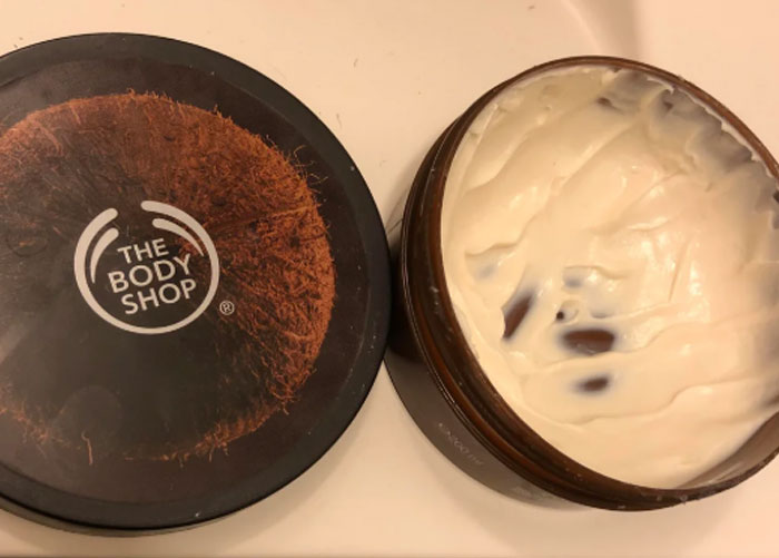 Open container of Body Shop cream showing white lotion inside, representing worst gifts people have ever received.