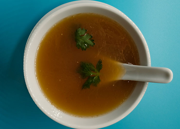 Bowl of brown soup with a white spoon and fresh herbs, illustrating one of the worst gifts ever received by people.