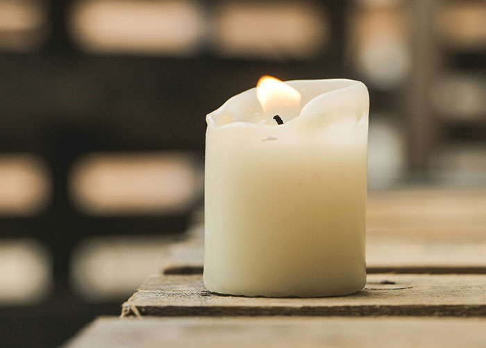White candle burning softly on a wooden surface illustrating the worst gifts people have ever received.