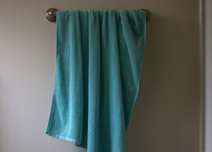 Blue textured towel hanging on a silver rod against a plain wall, illustrating one of the worst gifts ever received.