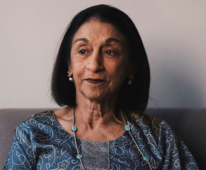 Elderly woman sitting thoughtfully indoors, illustrating themes of parenting and helicopter parenting behavior.
