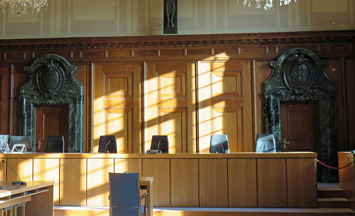 Courtroom interior with wooden paneling and chairs, captured in natural light, illustrating themes of helicopter parenting.