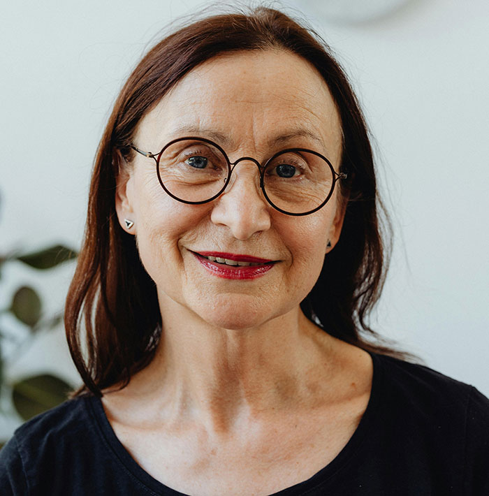 Middle-aged woman wearing round glasses and a black shirt, representing parents and helicopter parenting concepts.