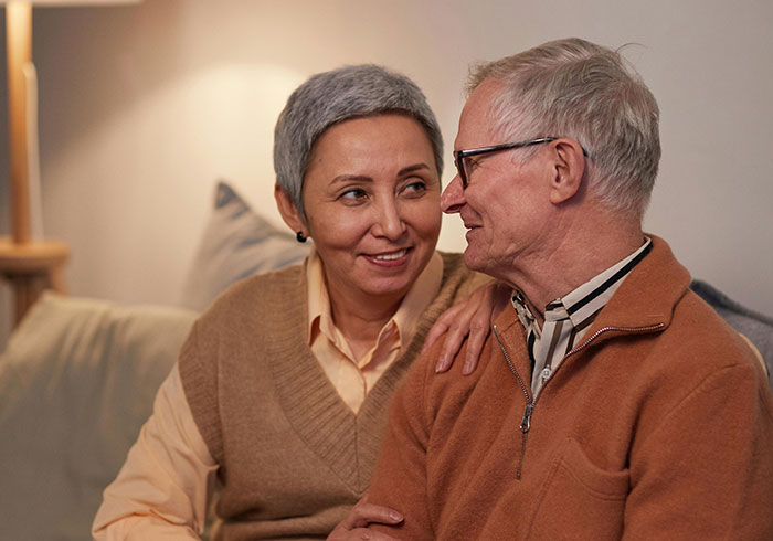 Older couple sitting together at home, showing warmth and care, representing helicopter parenting themes.