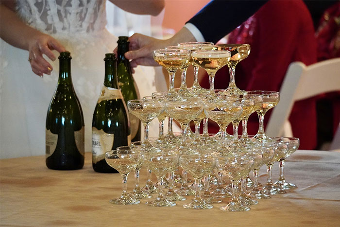 A wedding champagne tower being filled with sparkling wine, capturing a chaotic celebration moment at a wedding event.