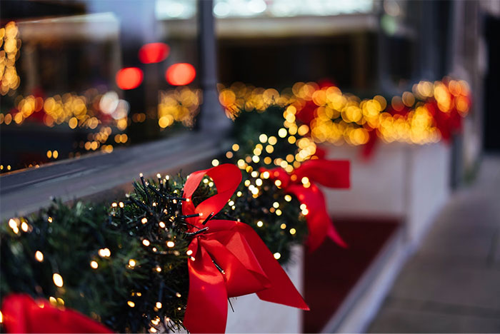 Holiday garland with red bows and twinkling lights decorating a window display in a festive chaotic wedding scene.