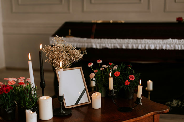 Candles and flowers arranged on a wooden table in a dimly lit room at a chaotic wedding event.