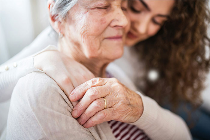 Older woman with a wedding ring being hugged by a younger woman, reflecting chaotic moments witnessed at a wedding.