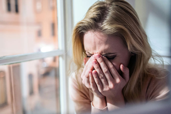 Young woman covering face in distress, reflecting on the most chaotic thing witnessed at a wedding event.