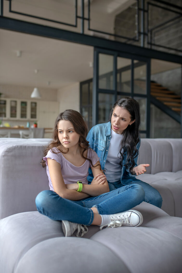 A mother speaking seriously to her upset daughter on a couch, illustrating hurtful things moms say to children.