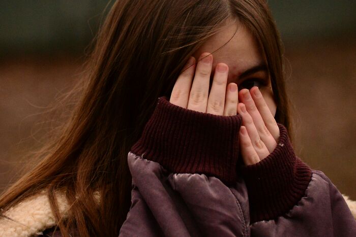 Teen girl covering her face with hands, expressing sadness and emotional hurt from the most hurtful things moms have said.