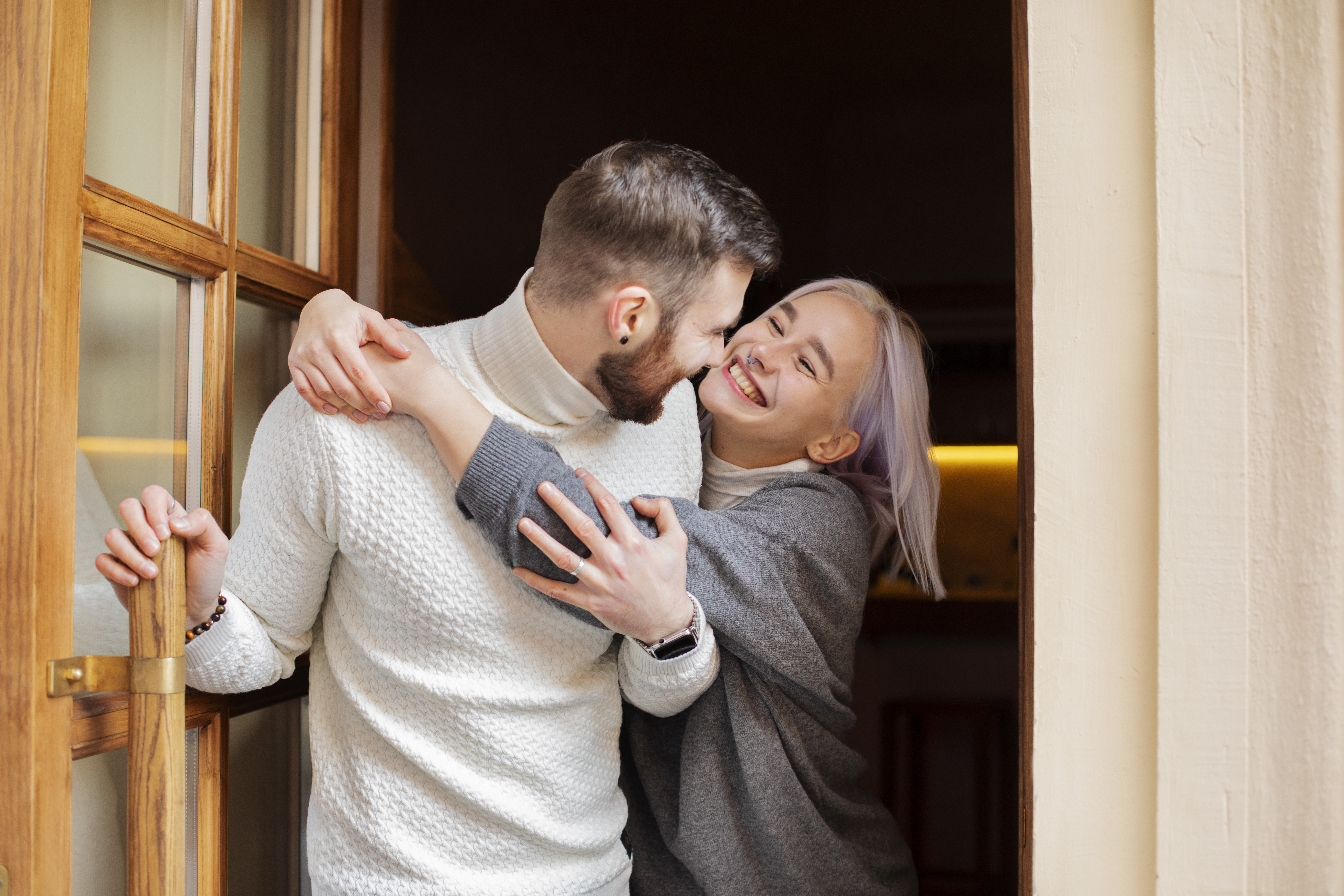 Couple sharing a close moment by a door, the husband unsure how to come clean about a lie from years ago.