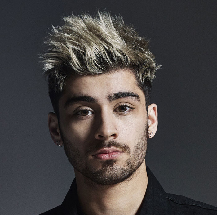 Young man with spiked blonde and black hair and earrings, former band member looks unrecognizable in this close-up portrait.