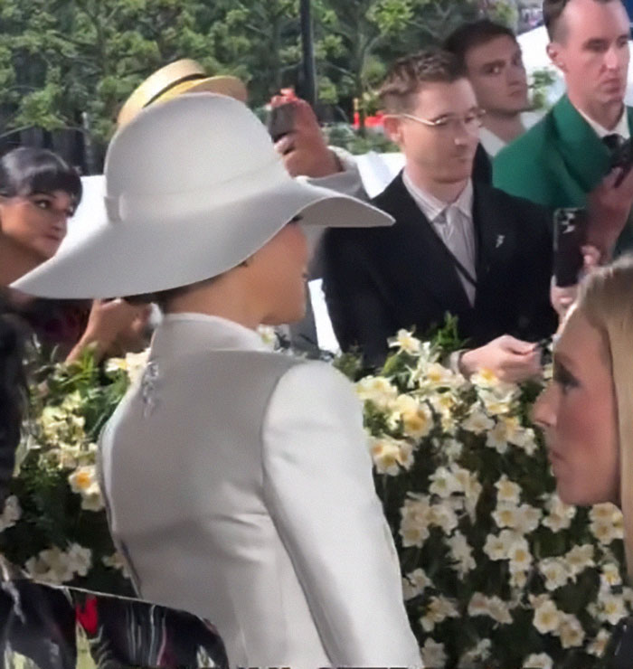Zendaya reacting in a white hat and outfit on the Met Gala red carpet, capturing a stunned moment among attendees.