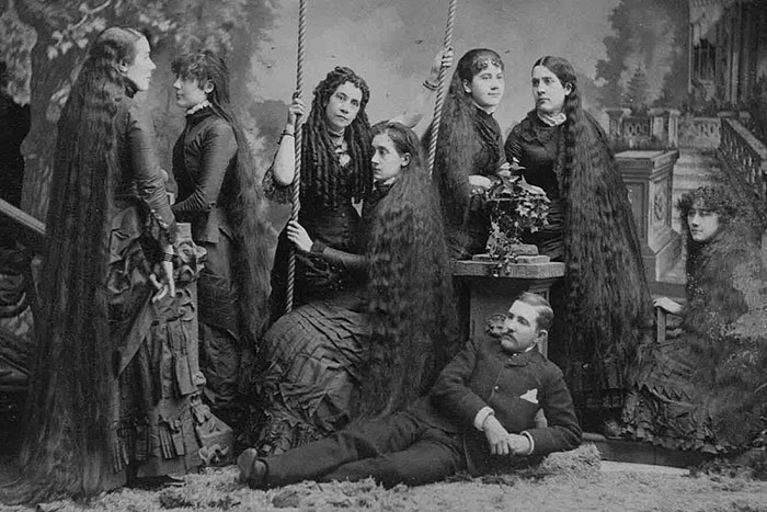 Group of Victorian women with extraordinarily long hair and a man, illustrating strange moments from Victorian times.