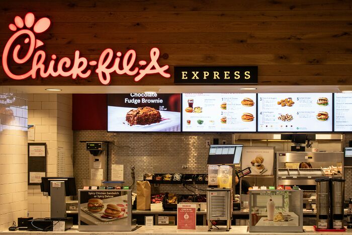 Chick-fil-A Express counter showing menu boards and food items in a fast food restaurant setting.