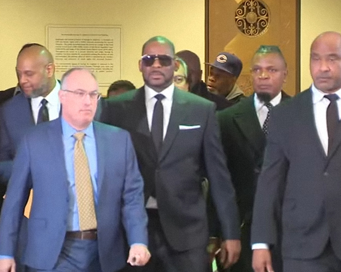 R Kelly walking with security and legal team in suits amid reports of prison overdose and assassination plot allegations. R Kelly walking with security and legal team in suits amid reports of prison overdose and assassination plot allegations.