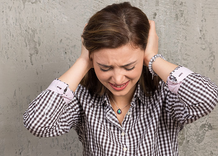 Woman covering ears in frustration, overwhelmed by loud and obnoxious MrBeast videos at home. Woman covering ears in frustration, overwhelmed by loud and obnoxious MrBeast videos at home.