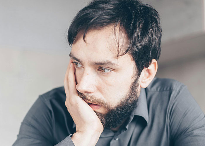 Man with beard and dark hair looking pensive and worried, possibly affected by wife cheating and mind control excuse.
