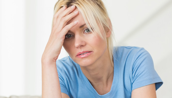 Stressed woman in blue shirt setting boundaries with friend after feeling used and overwhelmed by toddler hosting requests.