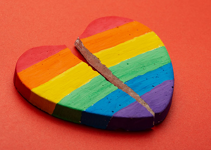 Broken heart painted with rainbow colors on red background, symbolizing woman blunt about travel with friend conflict. Broken heart painted with rainbow colors on red background, symbolizing woman blunt about travel with friend conflict.
