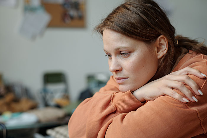 Woman looking upset and thoughtful indoors, reflecting on her wedding dress being ruined by her mother-in-law.