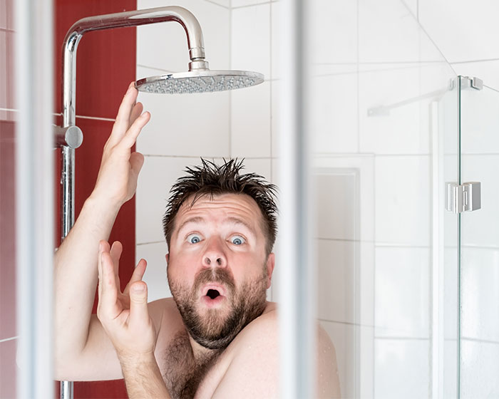 Man in shower reacting with surprise, illustrating a perfectly timed shower trick teaching a homophobic brother-in-law a lesson.