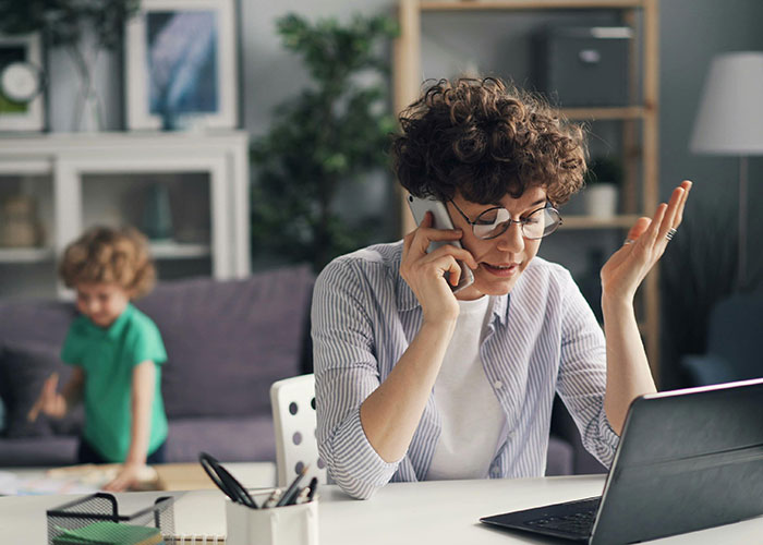 Woman assumes neighbor will babysit while being a SAHM, upset on phone call, child playing in the background at home.