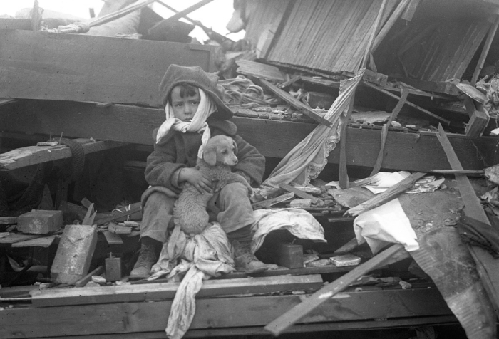Boy sitting among tornado debris holding a puppy, illustrating the worst tornado in US history with lives lost.