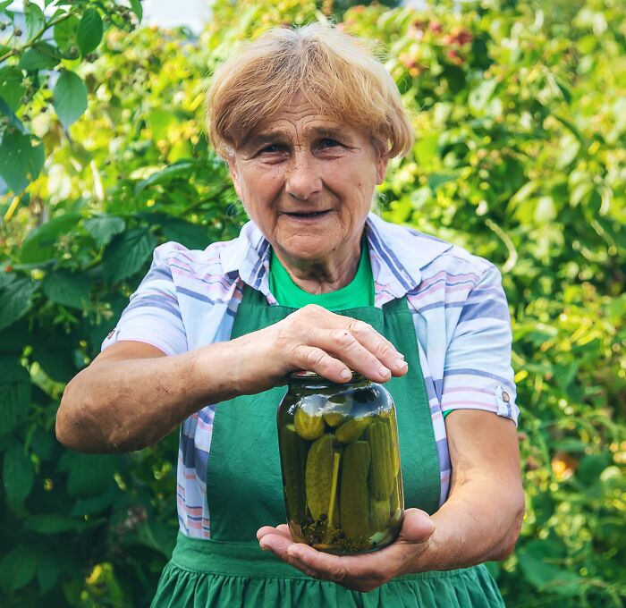 Elderly woman holding a jar of pickles outdoors, illustrating a humorous moment police got dragged into nonsense.