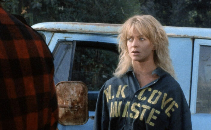 Woman with blonde hair looking concerned beside a vintage blue truck, illustrating toxic romantic movie scenes.