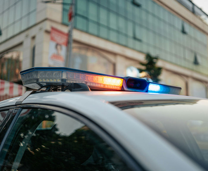 Police car with flashing lights in front of a modern building, relating to viral shooting incident in marriage context.
