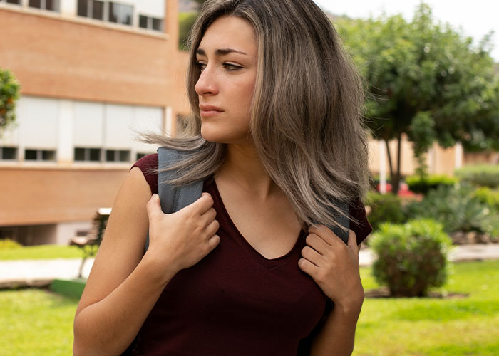 Young woman outside looking sideways with a serious expression, illustrating unhinged things men have said about their looks in public.