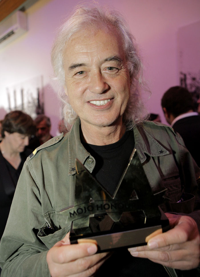 Older man with white hair holding a large award trophy at an indoor event, related to famous people controversies.