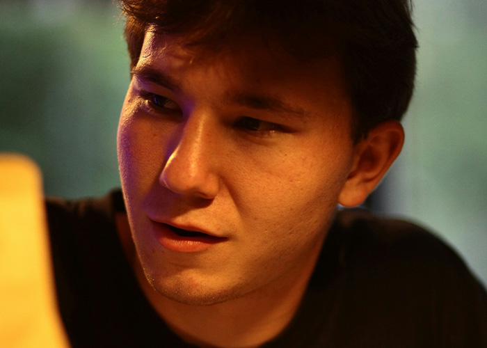 Young man with curious expression in warm light, capturing a moment that feels like another dimension on public transport.